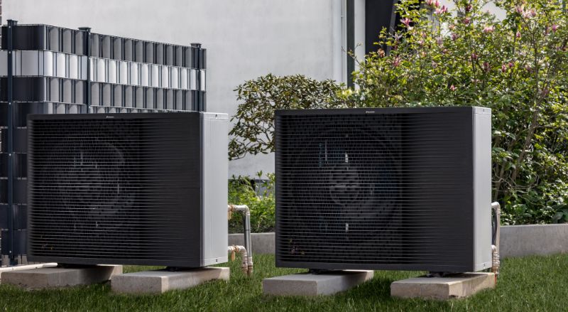 pompe a chaleur de marque daikin installee dans un jardin