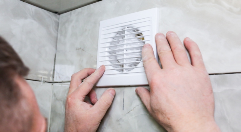 personne qui observe le système de ventilation dans une salle de bain