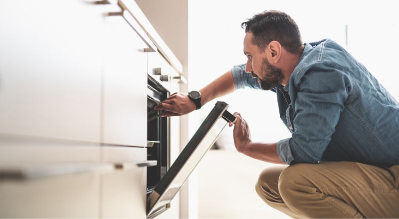 homme qui vérifie la cuisson des aliments dans son four