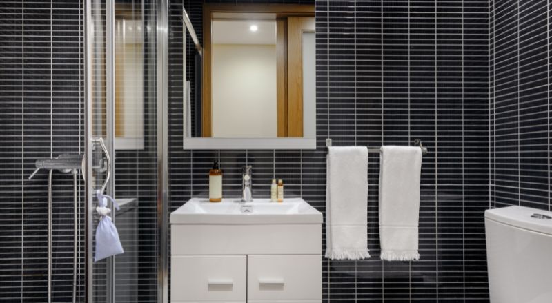 petite salle de bain de 2m2 avec un carrelage noir sur les murs pour agrandir la piece